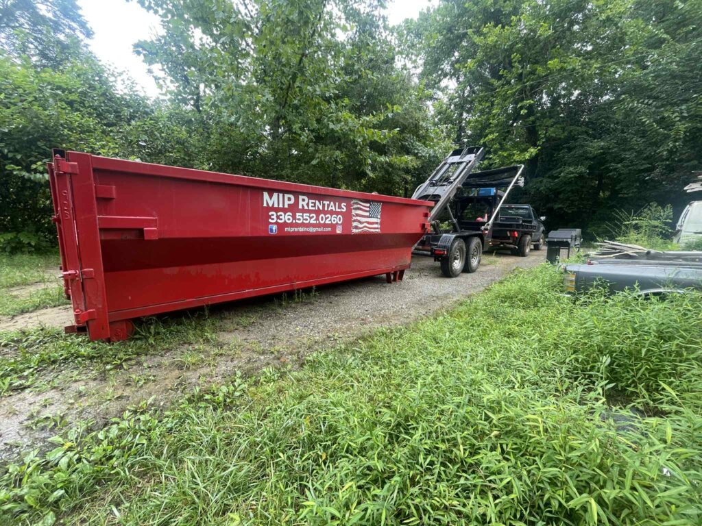 Local dumpster rental in North Carolina with MIP Rentals delivering a red roll-off dumpster.