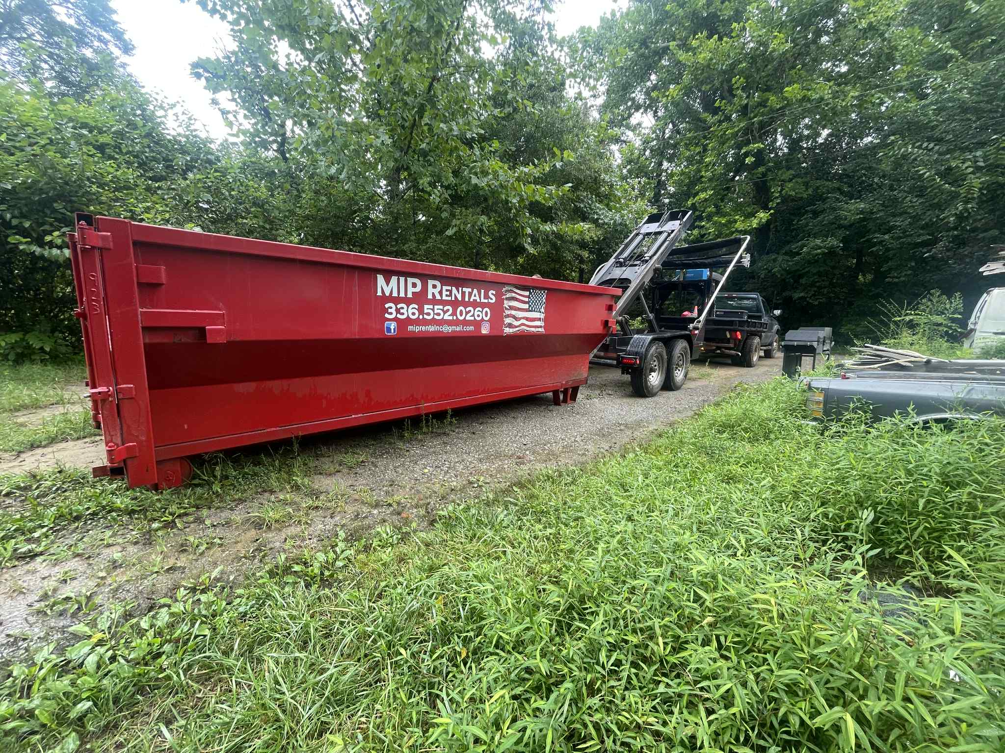 Local dumpster rental in North Carolina with MIP Rentals delivering a red roll-off dumpster.